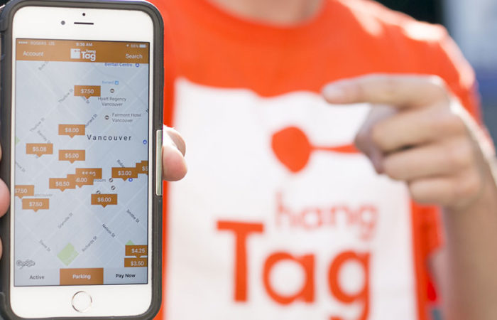 A man wearing a hangTag shirt points to a smartphone depicting hangTag's interactive map.